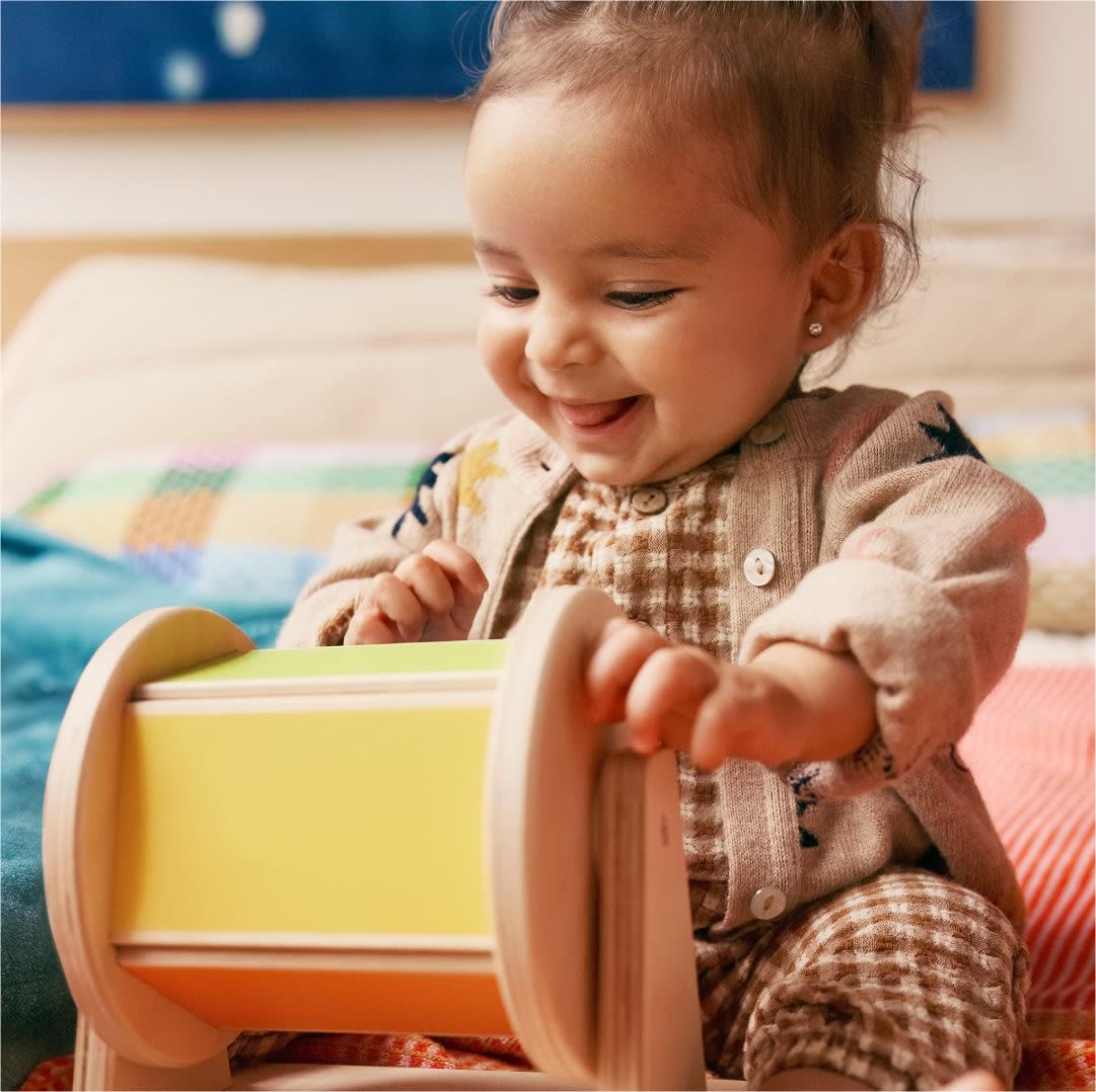 宝宝开心地转动彩虹转筒玩具 / A baby delighted by the rainbow spinner toy